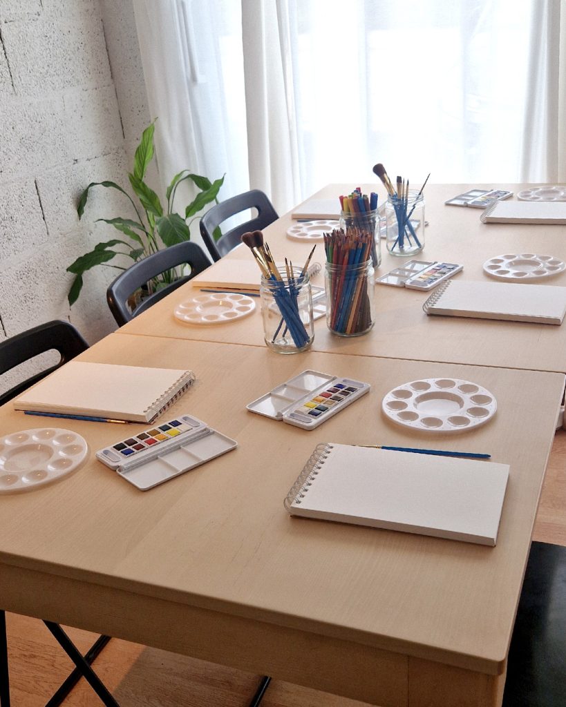 Vue d'ensemble de la table de travail et du matériel d'aquarelle installés pour accueillir les élèves de l'atelier libre d'aquarelle à L'Arbresle.