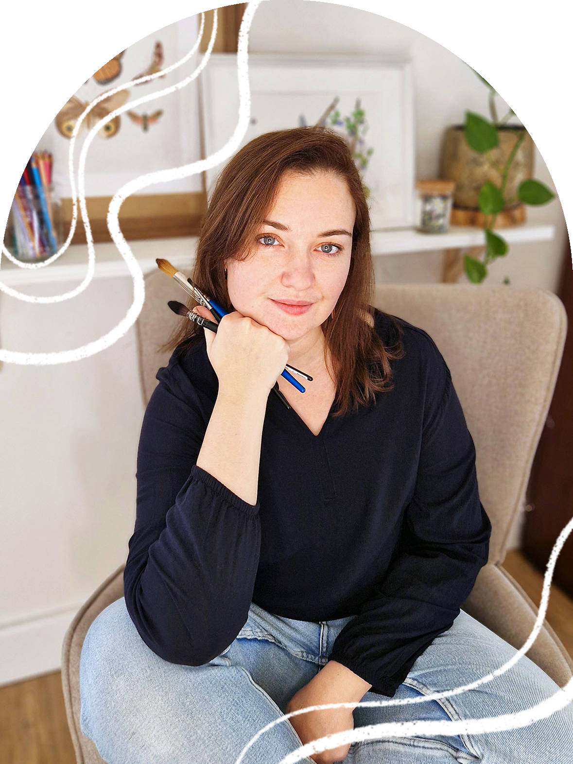 Elodie, artiste et professeure d'aquarelle, souriante dans son atelier à L'Arbresle, pinceaux à la main.